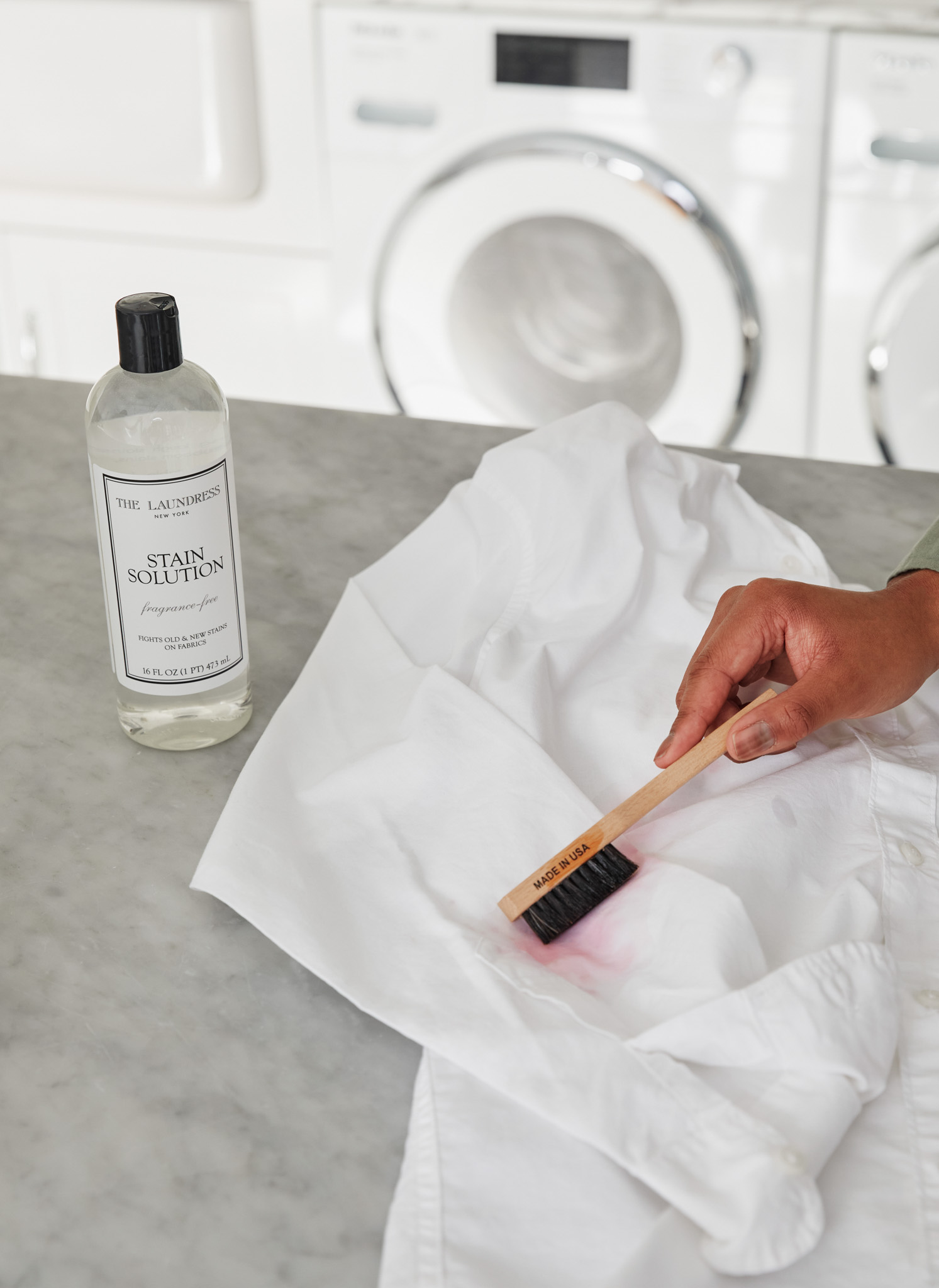 removing ink stain from white shirt with stain brush and the laundress stain solution