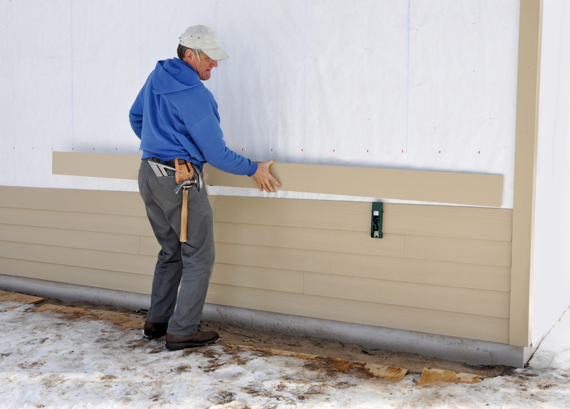 A person installing siding on a house.