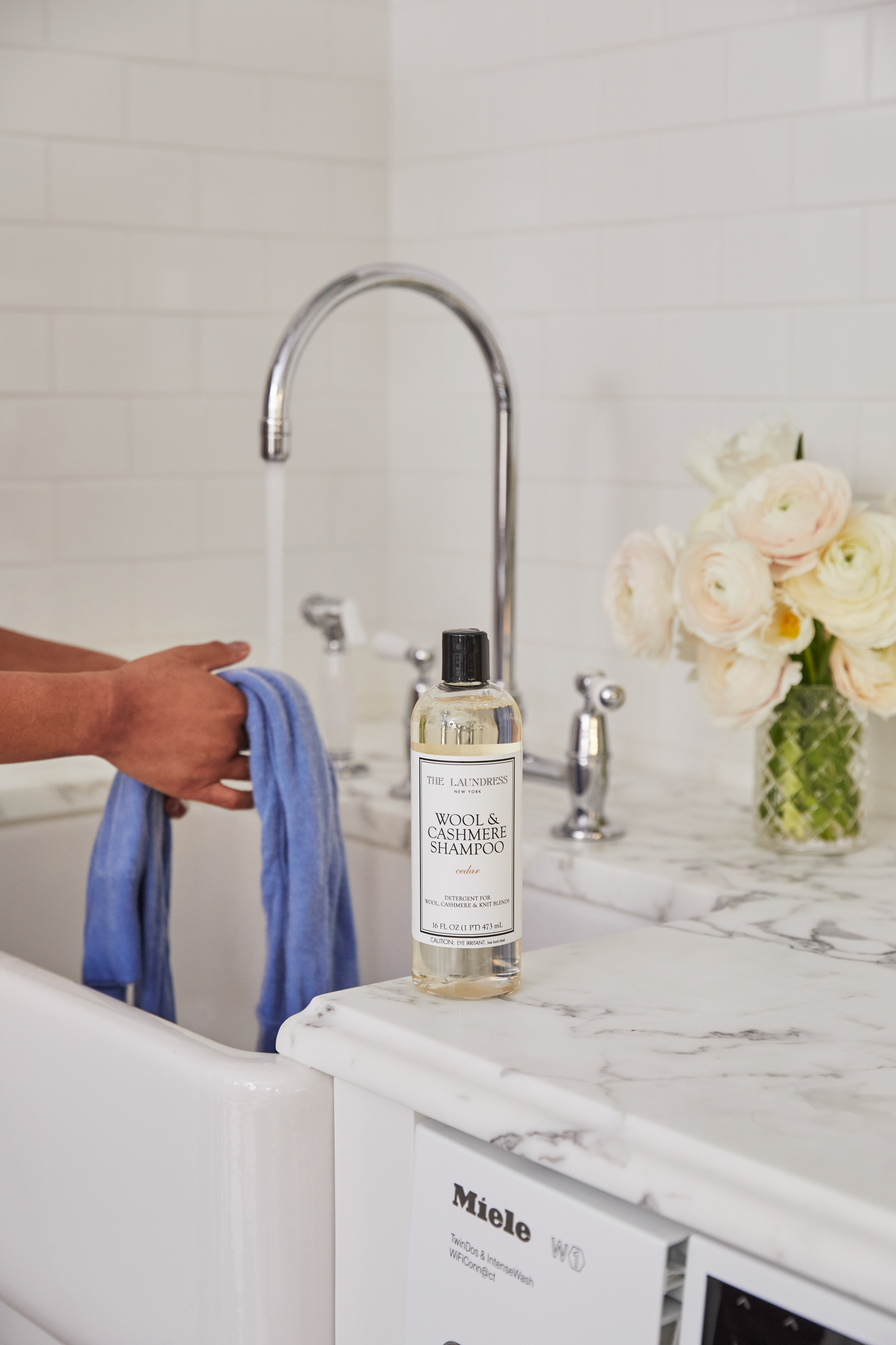 rinsing blue woolen fabric with the laundress Wool & Cashmere Shampoo on counter