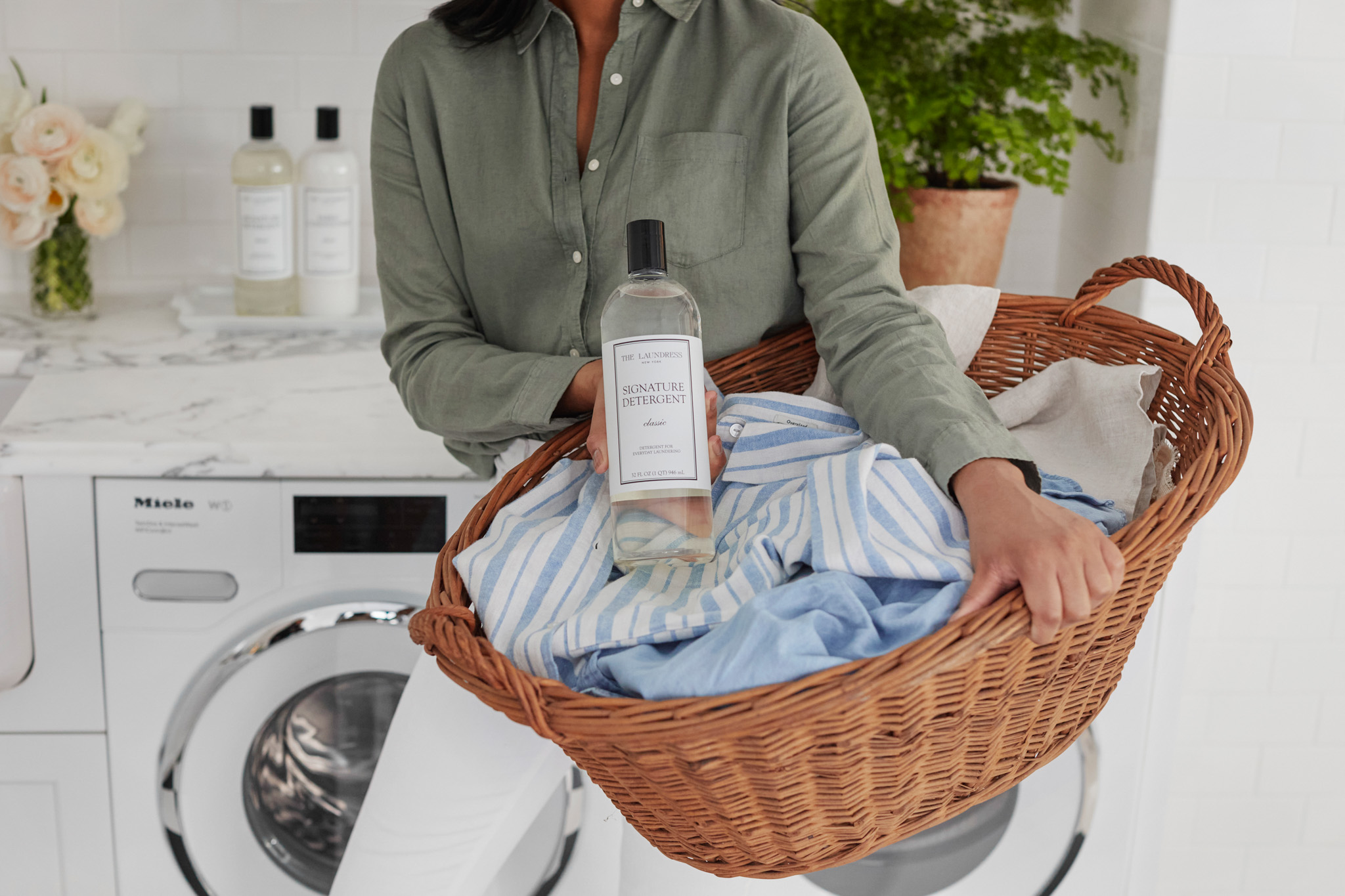 holding the laundress signature detergent in front of laundry hamper with dirty clothes