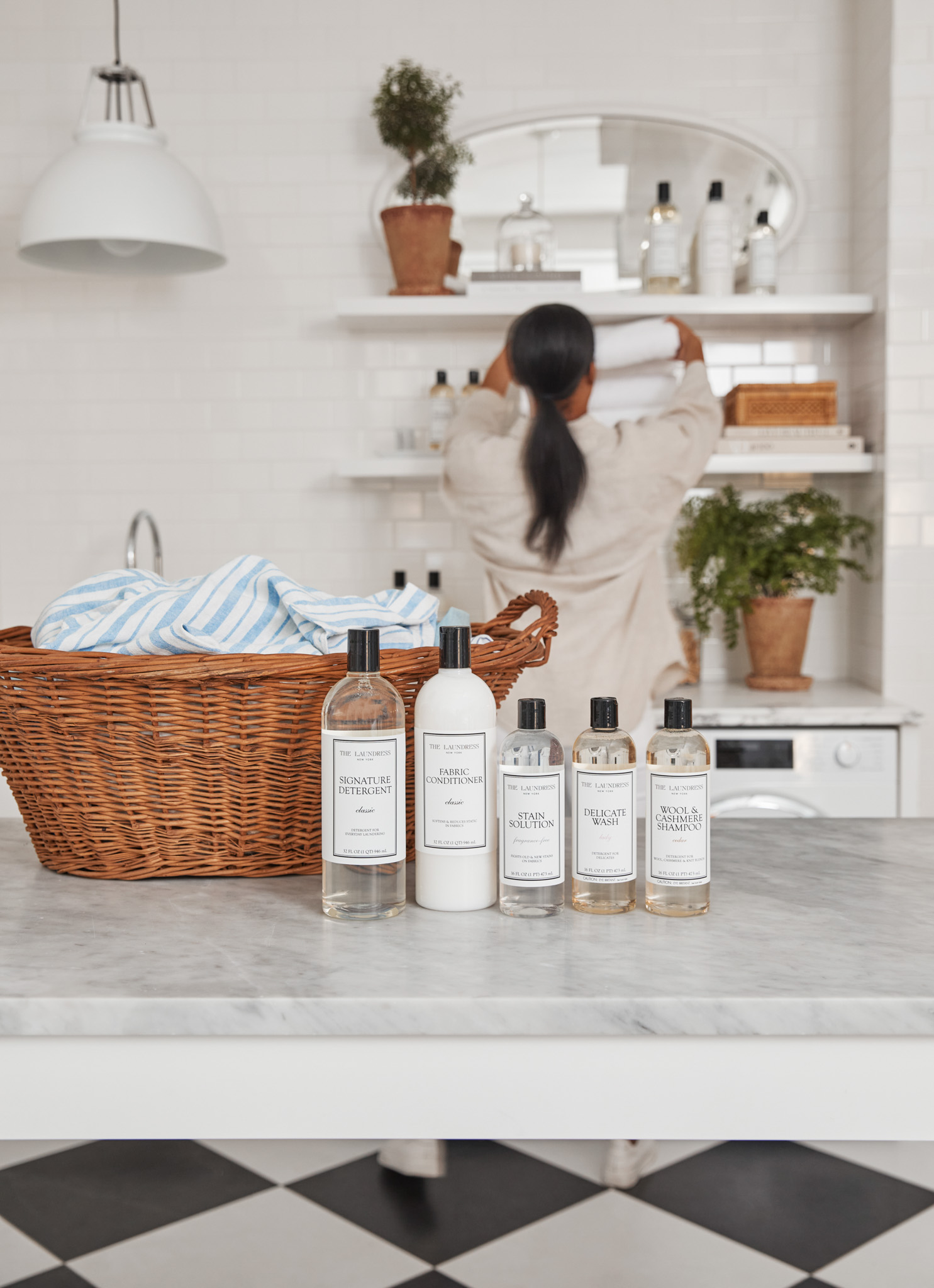 girl doing laundry with the laundress detergent collection on counter in front of woven laundry basket